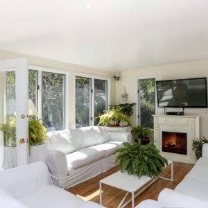 Bright living room in Hamlet Inn with elegant white furniture and a charming fireplace, inviting a cozy atmosphere.