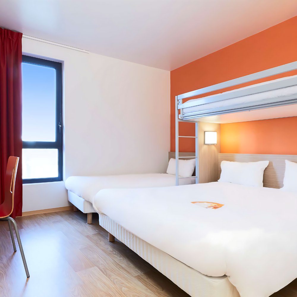 Cozy room at Hôtel Première Classe featuring two beds and vibrant orange walls, perfect for a cheerful stay.