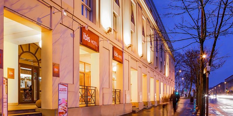 Ibis Versailles Château Hotel is seen from the street, highlighted by its eye-catching red sign.