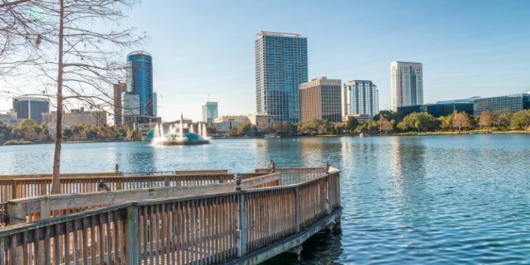 Orlando's skyline rises over Lake Eola, with a fountain dancing in a serene urban setting.