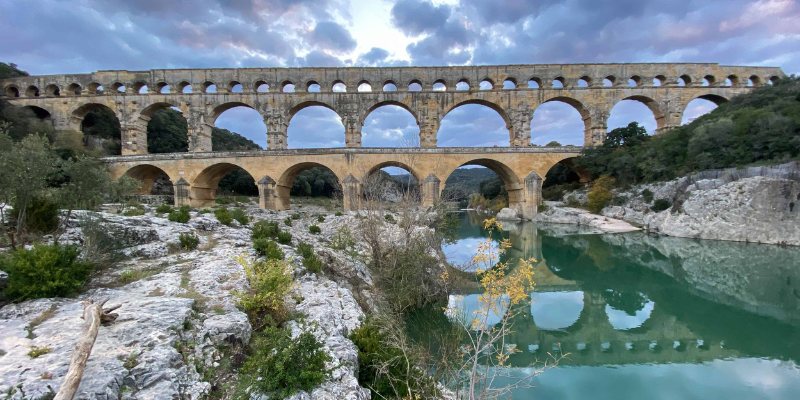 This image showcases the stunning Pont du Gard aqueduct reflected beautifully in calm waters.