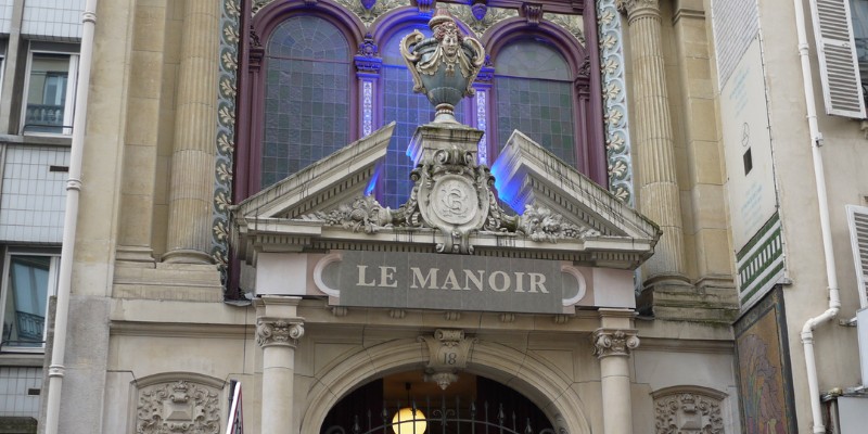 The entrance of Le Manoir de Paris, adorned with elegant design elements, beckons guests to discover its intriguing offerings.