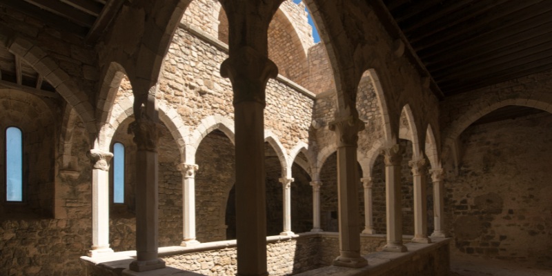 Inside view of a historic church on Lérins Islands, showcasing elegant arches and colorful windows.