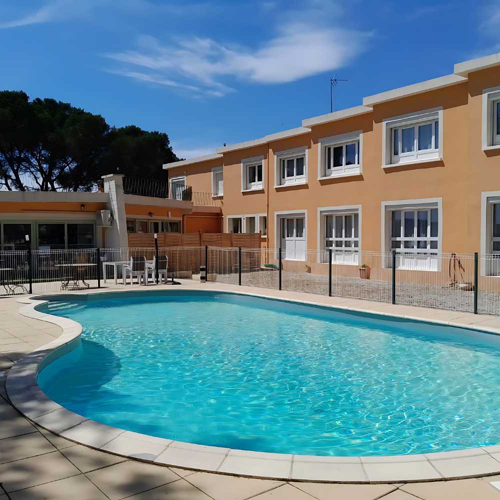 A beautiful pool located in front of Les Rocailles, enclosed by a charming fence, creating a peaceful atmosphere.