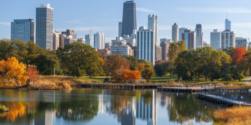 Lincoln Park's calm lake reflects the city skyline, blending nature with urban life beautifully.