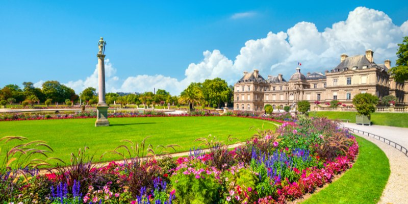 The exquisite gardens of the Louvre Palace in Paris, feature colorful blooms and serene pathways in a historic setting.