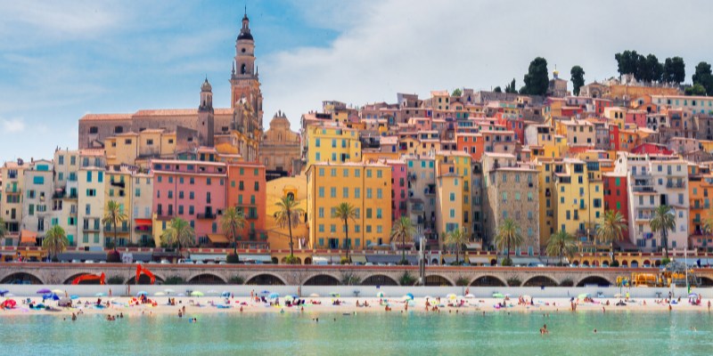 Menton showcases a lively beachside city with an array of colorful buildings against a sunny backdrop.