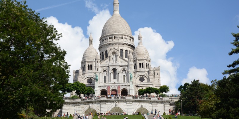 A view of the Sacré-Cœur Basilica in Montmartre, Paris, highlighting its stunning architecture and scenic surroundings.