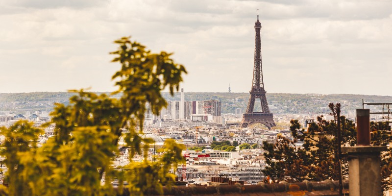 The Eiffel Tower rises majestically in the distance, viewed from the charming neighborhood of Montmartre in Paris.