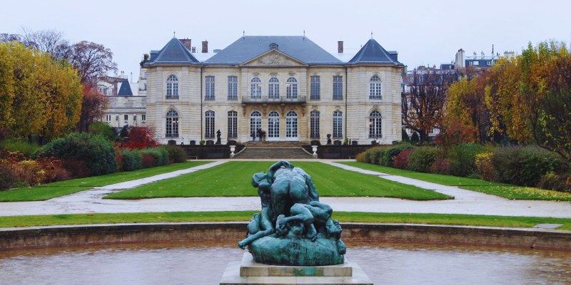 The Musée Rodin features a striking statue in front, framed by verdant trees and an impressive building structure.