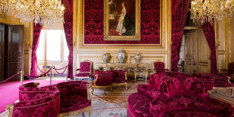 The opulent Napoleon III Apartments feature a room decorated in luxurious red velvet and striking gold details.