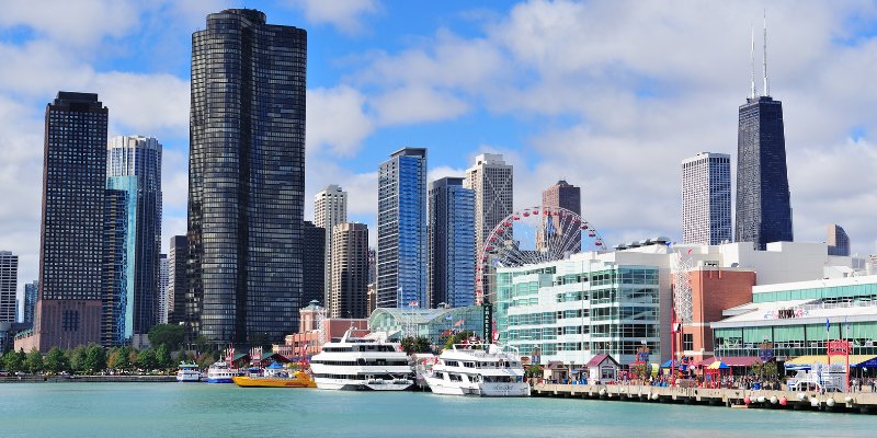 Skyline of Chicago with Navy Pier, featuring a Ferris wheel and boats in the foreground.