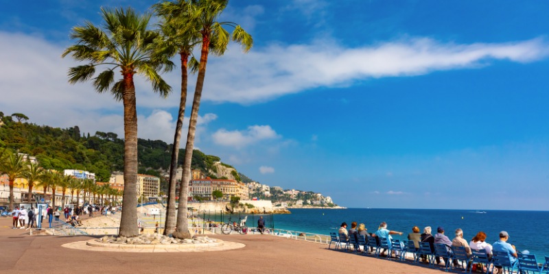 Visitors walk along the beach at Promenade des Anglais, experiencing the beauty of Nice, France.