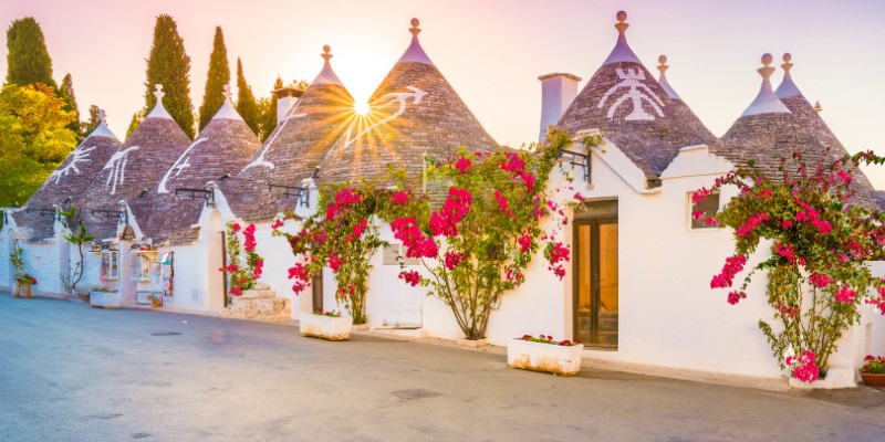 Trulli houses in Puglia, Italy, showcasing unique conical roofs and traditional stone architecture against a clear sky.