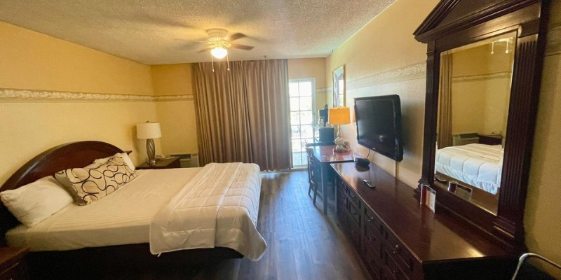 Stylish queen room with a bed, dresser, and television, designed for a pleasant hotel experience.