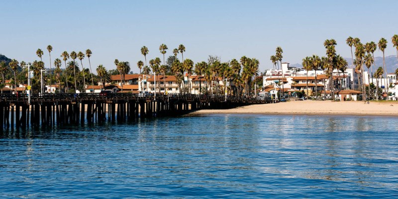 Santa Barbara's pier features swaying palm trees and charming buildings in the background, showcasing a beautiful seaside view.