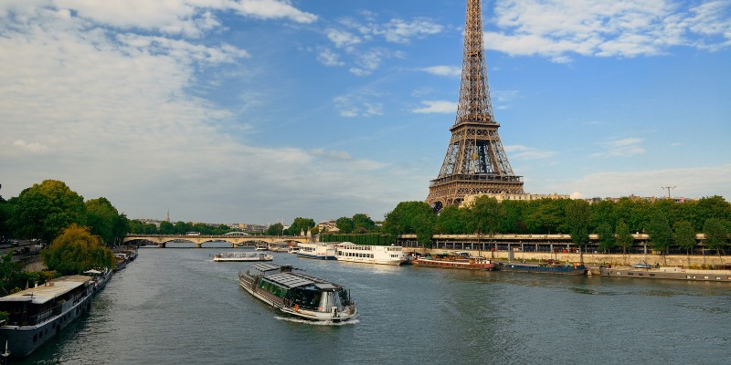 The iconic Eiffel Tower stands tall in Paris, France, alongside a boat cruising on the Seine River.