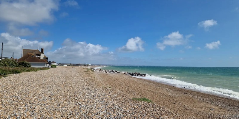 Shoreham Beach showcases a pebbled shore with a picturesque house nestled by the water's edge.