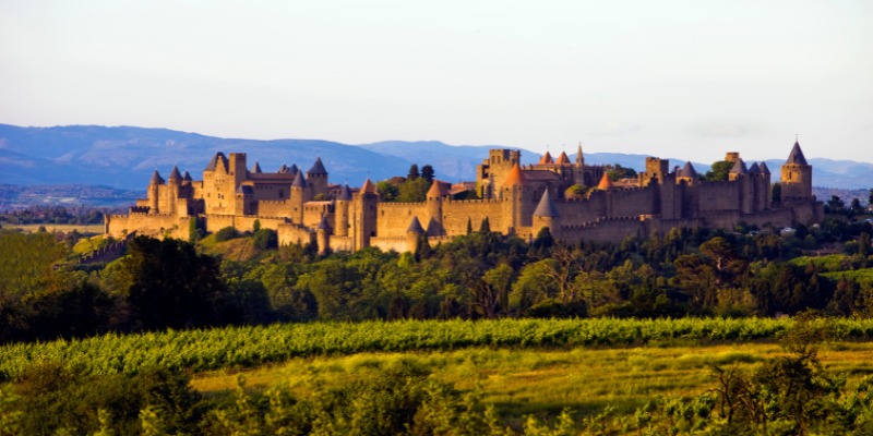 A castle atop a hill, encircled by lush trees, showcasing the beauty of Carcassonne in shoulder season