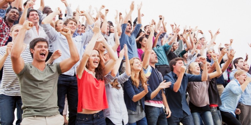 A lively crowd of people cheering and waving their hands, promoting awareness in busy environments.