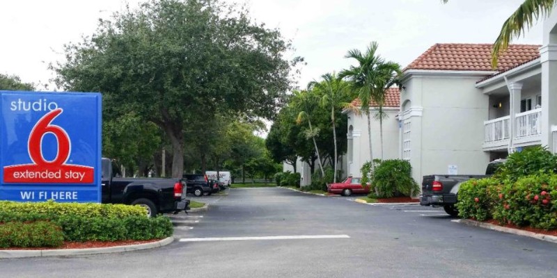 Exterior view of Studio 6 West Palm Beach FL, showcasing its welcoming entrance and surrounding landscape.