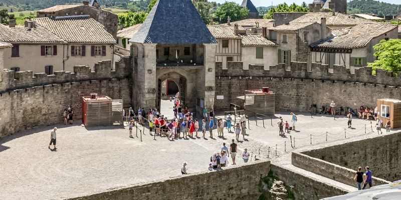 The medieval city of Avignon in summer, featuring historic buildings and bustling streets filled with visitors enjoying the sun.