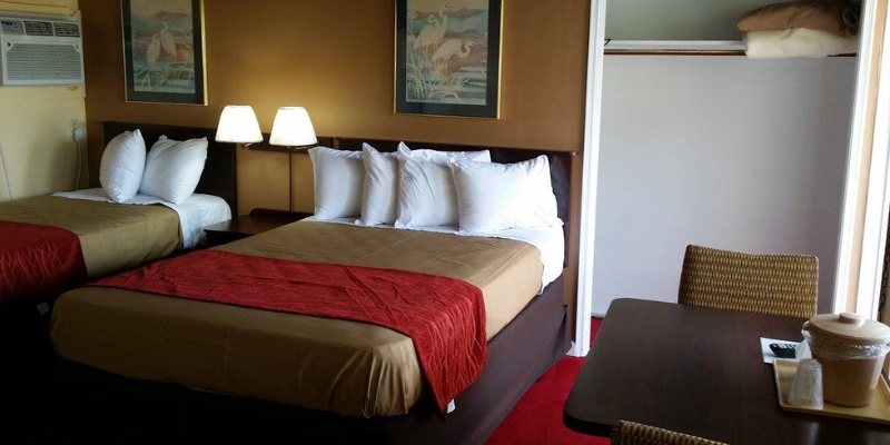 Two beds in a hotel room with a desk, creating a cozy and functional space for guests.