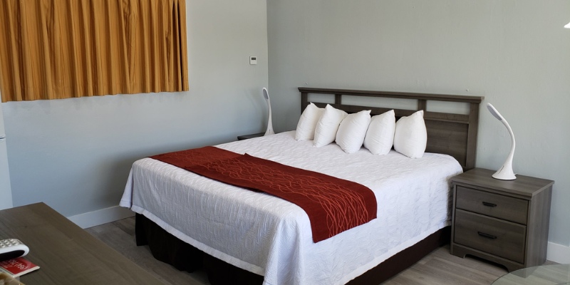 A neatly made bed with white sheets and bright red pillows, creating a warm and inviting atmosphere.