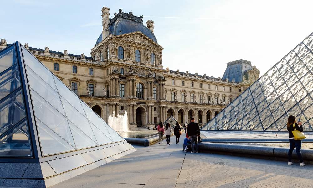 The Louvre Museum in Paris, France, showcasing its iconic glass pyramid entrance and historic architecture.