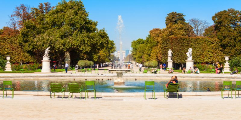 Tuileries Garden features a fountain at its center, with inviting green chairs arranged around it.