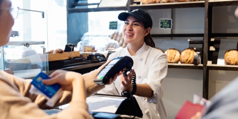 A woman is seen paying for her coffee with a credit card, highlighting a typical local practice in coffee shops.