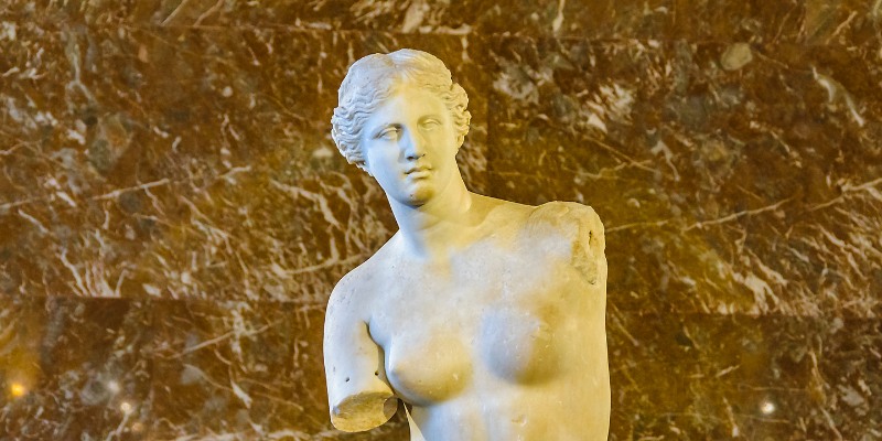 The Venus de Milo, a renowned marble statue of a woman, elegantly positioned in a museum setting.