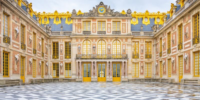 A view of the Palace of Versailles courtyard, highlighting its majestic design and lush surroundings in France.