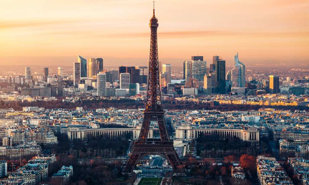 Paris cityscape at sunset featuring the Eiffel Tower, showcasing vibrant colors and iconic architecture.