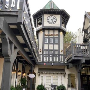 A charming clock tower stands tall in the courtyard of Wine Valley Inn, surrounded by lush greenery and inviting ambiance.