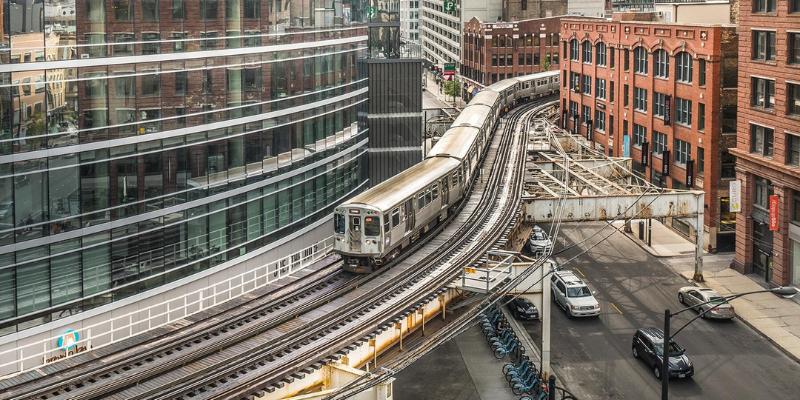 A train moves along the tracks in a bustling Chicago cityscape, showcasing public transportation.