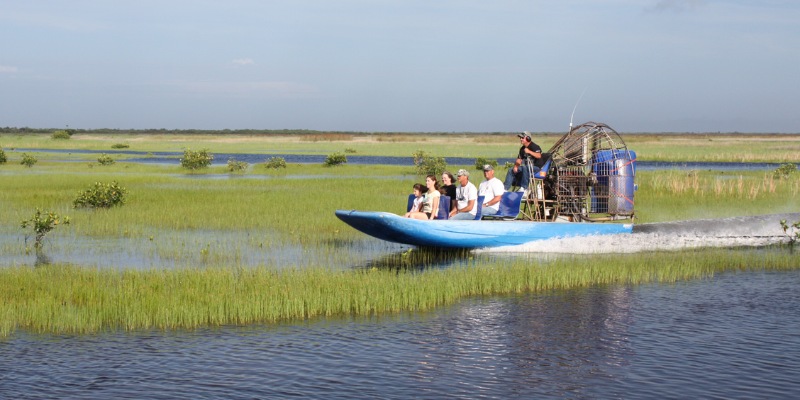 Tourists ride in an airboat through the marsh and experience Captain Mitch’s Airboat Tours adventure.