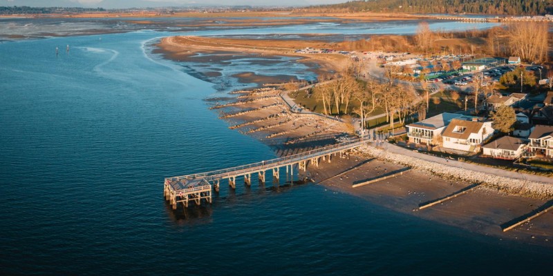 Overhead shot of Crescent Beach, Florida, featuring a pier and coastal homes by the water's edge.