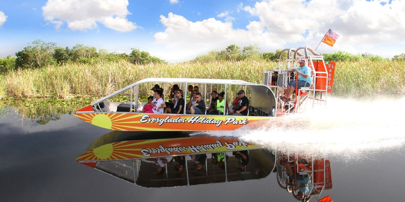 Tourists riding an airboat on a lake, surrounded by the natural beauty of Everglades National Park.