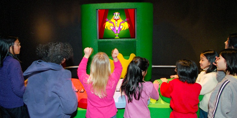 A group of kids plays with a television at the Grossology Exhibit in MOSI, exploring fun and educational activities.