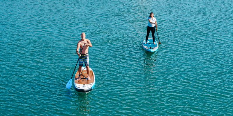 Two paddle boarders navigate the water at Fort Zachary Taylor State Park, enjoying a peaceful day on the water.