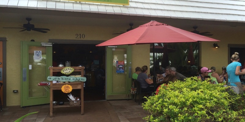 Guests relax at Sun Garden Cafe in Siesta Key Beach, sitting outdoors beneath a colorful umbrella.