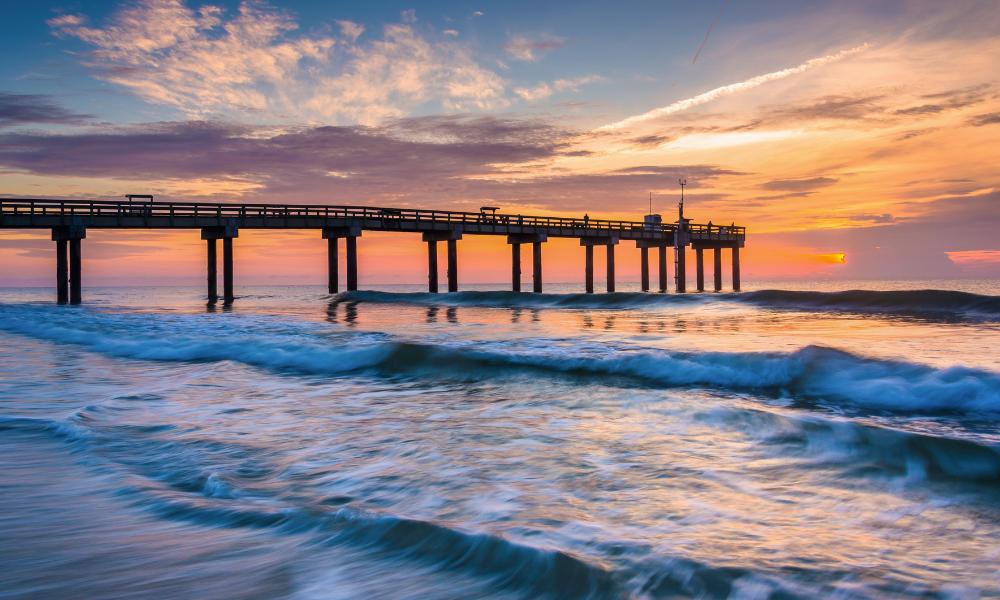 A calm pier at sunset with waves crashing, reflecting the natural beauty of St. Augustine's coastal scenery.