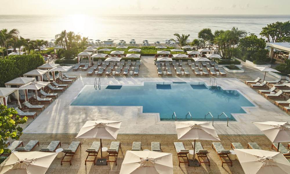 A stunning pool at the Ocean View Hotels at West Palm Beach for Rent, surrounded by palm trees and offering a breathtaking ocean view.