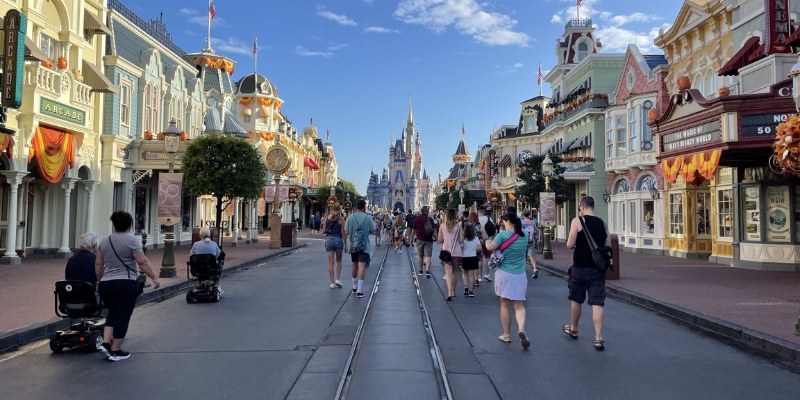 A tourist enjoying a sunny day at Disneyland, surrounded by vibrant attractions and summer crowds.