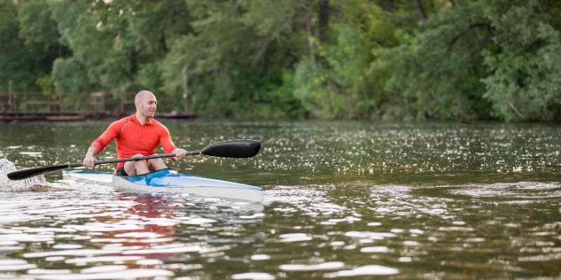 A man kayaking on a calm lake in Manatee Springs State Park, surrounded by lush greenery in Chiefland, Florida.