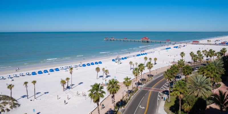 View of Clearwater Beach with its sandy shore, clear blue water, and a wooden pier inviting visitors to enjoy the day.