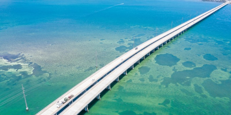 Bird's-eye view of the Key West bridge, showcasing the surrounding turquoise waters and lush landscape.