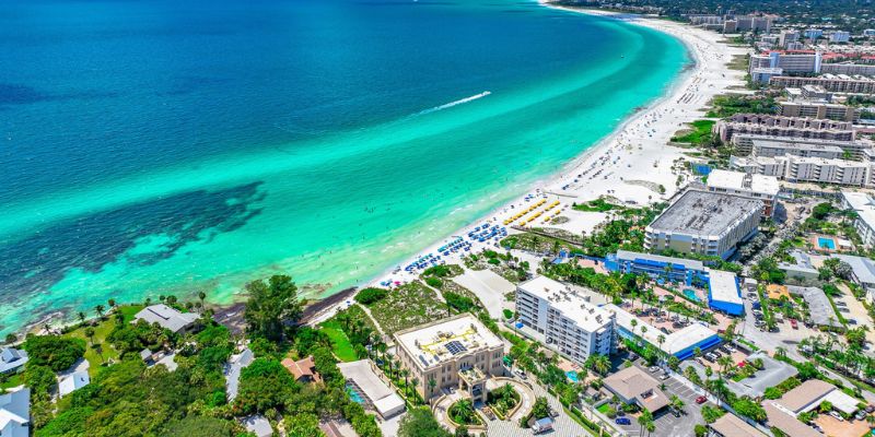 Overhead shot of Siesta Key beach showcasing the sandy shore and turquoise ocean, with gentle waves lapping the coast.