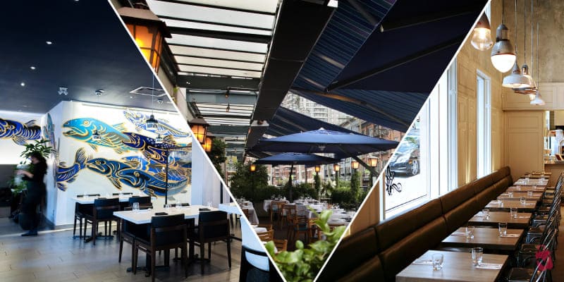 A restaurant with large windows offering a view of a harbor with ships and industrial cranes. The interior features wooden floors, modern tables and chairs, and decorative lighting.